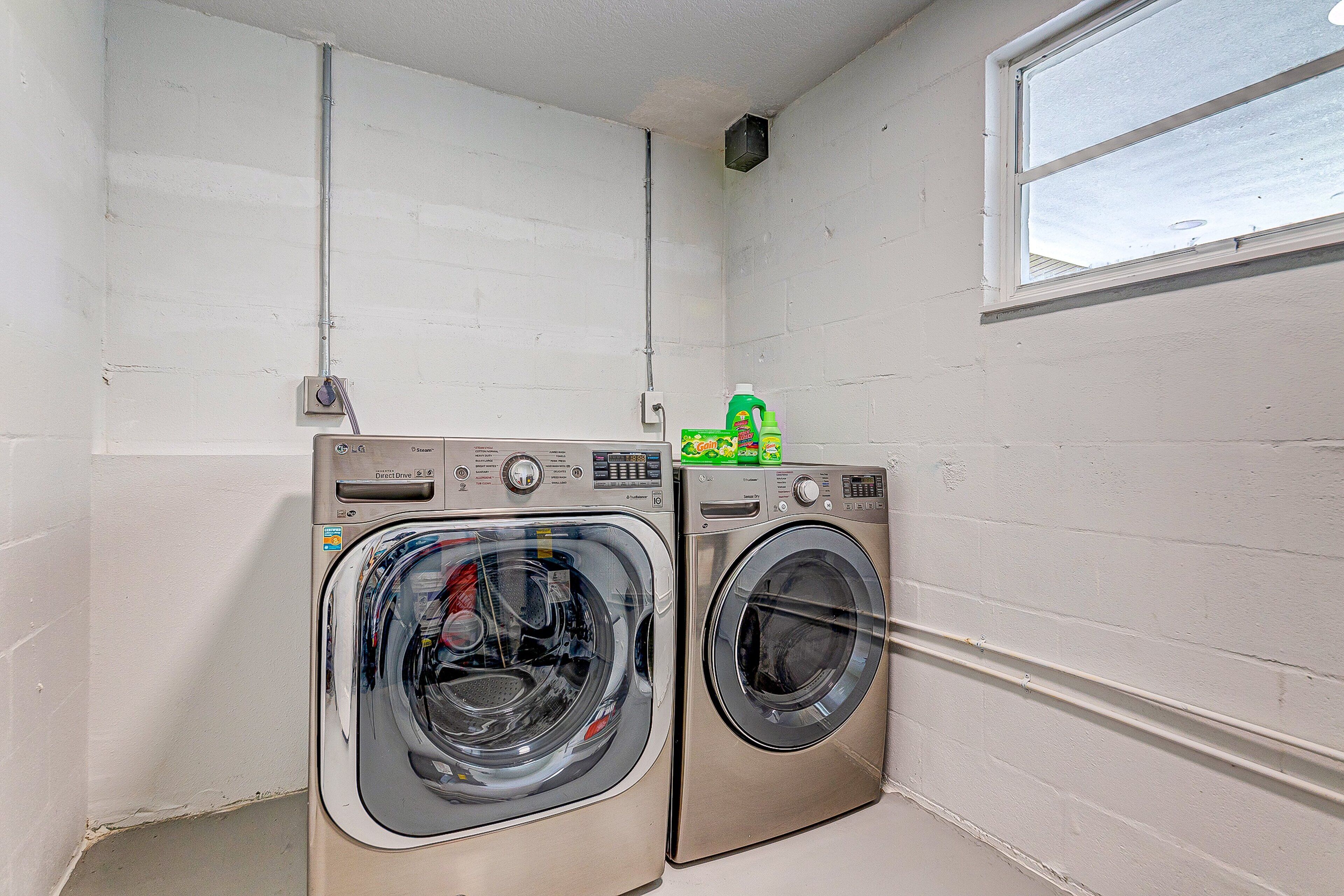 Two front-loading washing machines in a laundry room with white walls and a window.