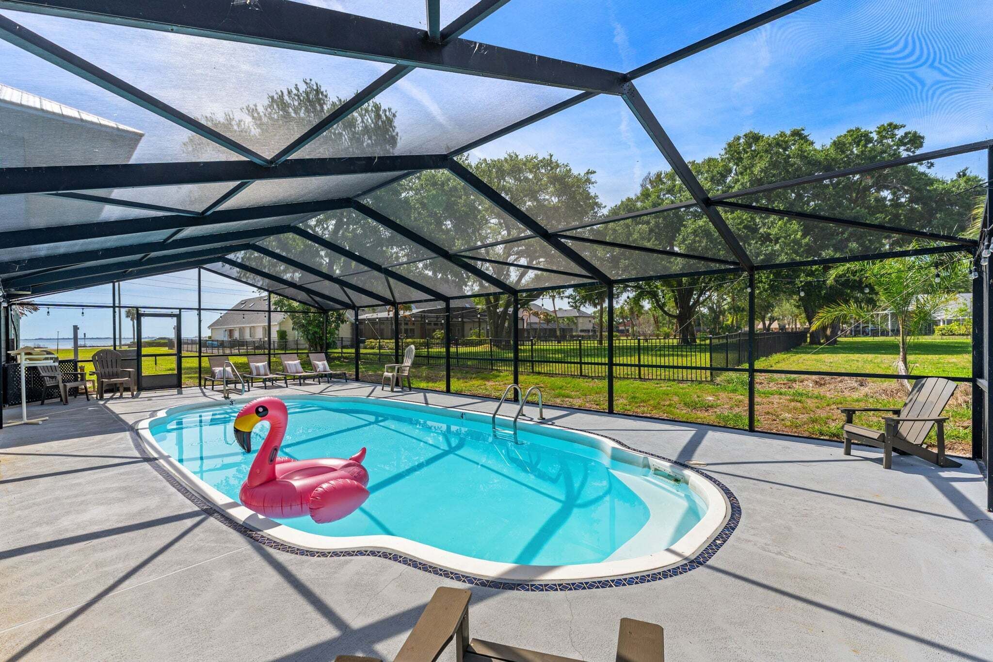 Una piscina techada con un flotador de flamenco, sillas de descanso y vistas al exterior.