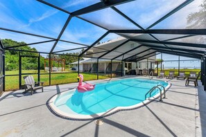 Una piscina interior con un flotador de flamenco, rodeada de sillas y una zona cubierta.