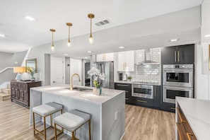 A modern kitchen with a central island, stainless steel appliances, and pendant lighting. - 1790 S. Tropical Trail (Merritt Island)
