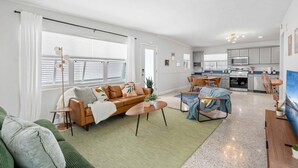 Ein modernes Wohnzimmer mit einer Couch, einem Couchtisch und einem Essbereich mit Stühlen.