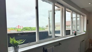 Een kamer met een groot raam, een radiator, een handdoekhouder en een kamerplant.
