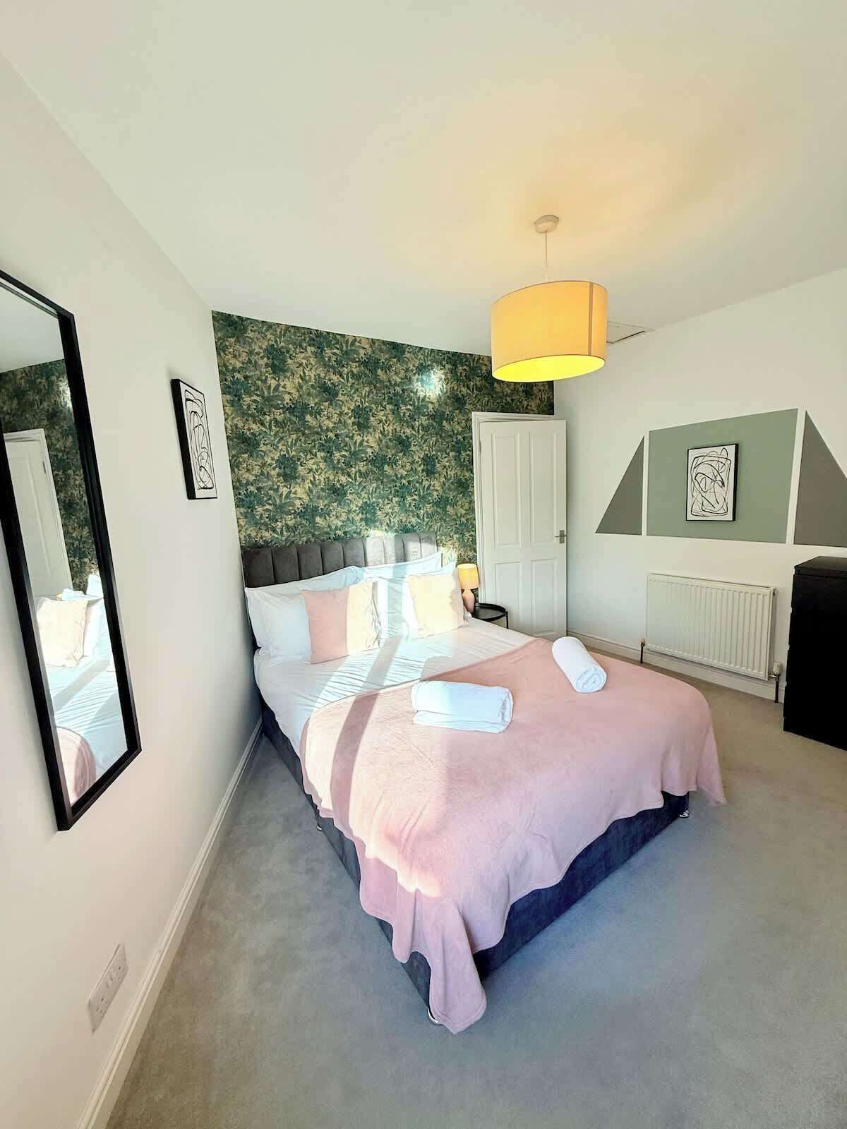 A bedroom with a bed, a mirror, a radiator, and artwork on the walls.