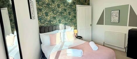 A bedroom with a bed, a mirror, a radiator, and artwork on the walls.
