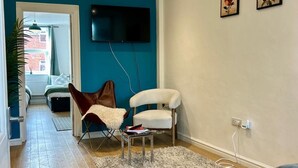 Ein Wohnzimmer mit Flachbildfernseher, zwei Sesseln, einer Couch und einem Teppich.