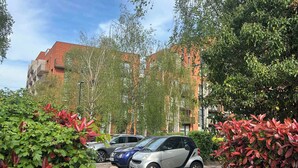 Ein Parkplatz mit Autos, ein Gebäude mit roten Backsteinfassaden und Bäumen.