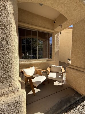 Eine sonnendurchflutete Terrasse mit zwei Holzstühlen und einem großen Fenster.
