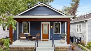 A house with a covered porch, two chairs, a small table, and a potted plant. - Chic Music City Retreat & Studio (Nashville)