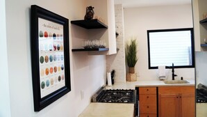 A kitchen with a framed color palette, a gas stove, wooden cabinets, and a window with blinds. - Chic Music City Retreat & Studio (Nashville)