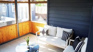A sunlit room with a wooden bench, a white sofa with striped pillows, and a potted plant. - Chic Music City Retreat & Studio (Nashville)