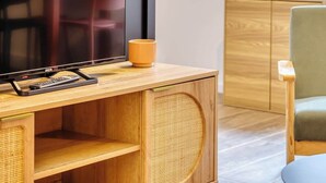 A wooden desk with a television, remote control, and a mug. - Gathéa, studio rénové pour 2 proche du Vieux marché (Rouen)