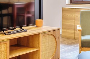 A wooden desk with a television, remote control, and a mug. - Gathéa, studio rénové pour 2 proche du Vieux marché (Rouen)