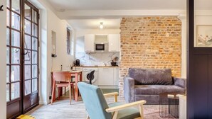 A modern living space with a kitchen, a dining area, and a seating area with a sofa and chairs. - Gathéa, studio rénové pour 2 proche du Vieux marché (Rouen)