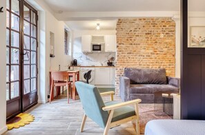 A modern living space with a kitchen, a dining area, and a seating area with a sofa and chairs. - Gathéa, studio rénové pour 2 proche du Vieux marché (Rouen)