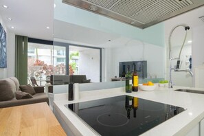 Eine moderne Küche mit integriertem Induktionskochfeld, einem großen Fenster und einem Essbereich mit einer Sitzecke.
