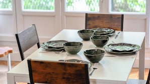 Una mesa de comedor con varios cuencos y cubiertos, rodeada de sillas.