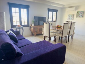 Ein Wohnzimmer mit einer Couch, einem Esstisch, Stühlen, einem Fernseher und einem dekorativen Schrank.