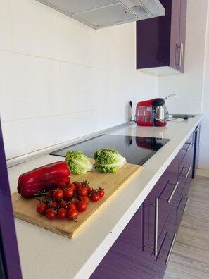Eine Küche mit Schneidebrett, roter Paprika, Salat und Kirschtomaten.