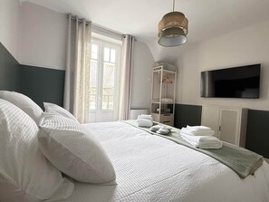 Ein Hotelzimmer mit Bett, Fernseher, Kleiderschrank und einem fenster mit Vorhängen.