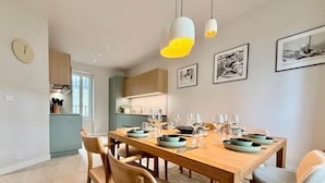 Un comedor moderno con una mesa de madera dispuesta para seis personas, rodeada de sillas con asientos acolchados.