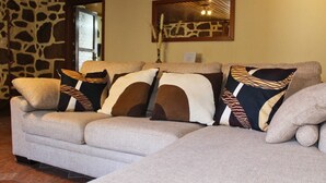 A sectional sofa with patterned cushions, a stone wall, and a mirror on the wall.