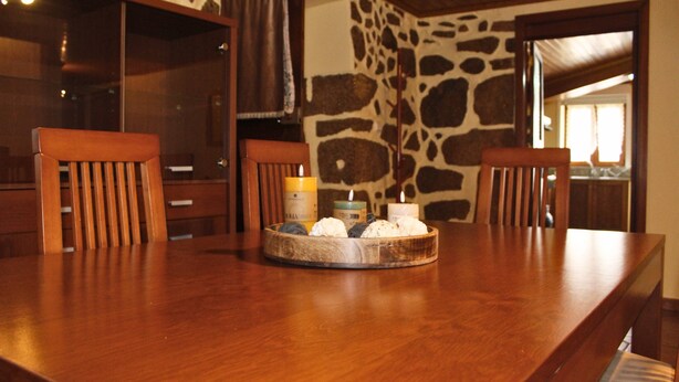 A wooden dining table with chairs, a candle, and a tray with candles.
