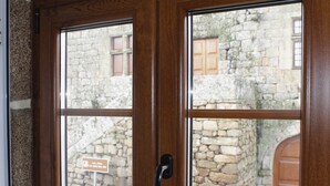 A wooden door with glass panels, a metal handle, and a stone wall visible through the glass.