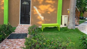A building with a brown facade, a green door, and a bench in the front yard.