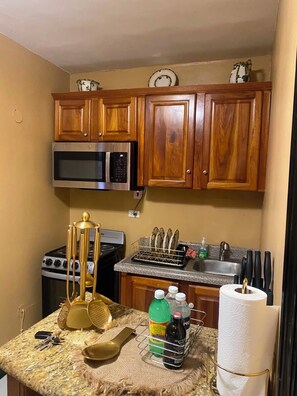 A kitchen with wooden cabinets, a microwave, a stove, and a sink. - Montego Bay Ironshore Luxury  GOLD ROOM (Montego Bay)