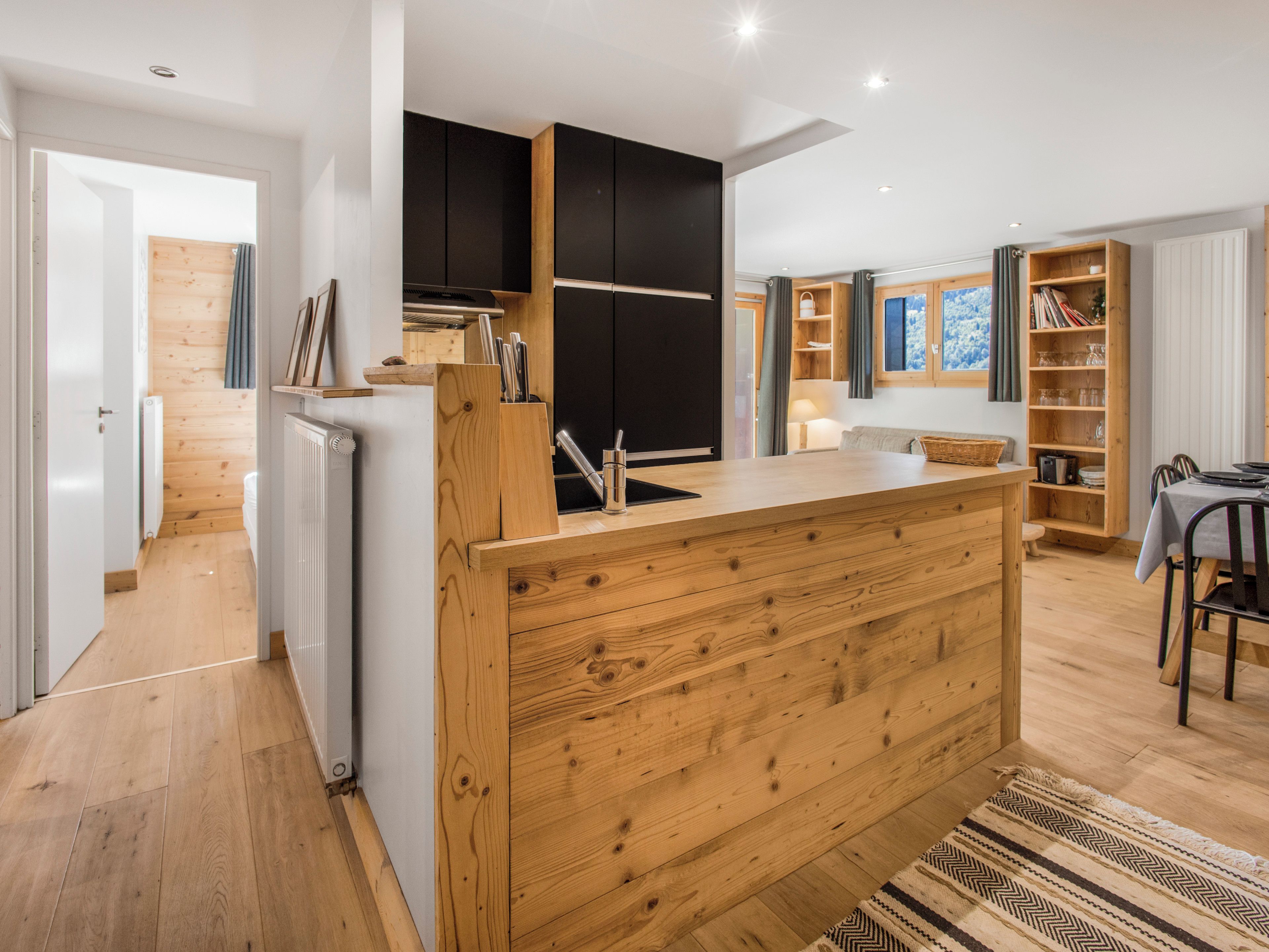 Une cuisine moderne avec des meubles en bois, un îlot central et un coin repas comprenant une table et des chaises.