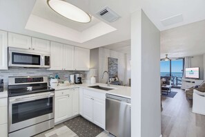 A modern kitchen with stainless steel appliances, a dishwasher, and a view to a balcony with outdoor seating. - Super Clean, Pool, Beach, Dining, Fun (Orange Beach)