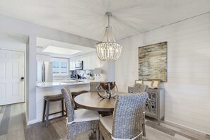 A modern kitchen with white cabinetry, a central island, and a chandelier. - Super Clean, Pool, Beach, Dining, Fun (Orange Beach)