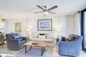 A living room with a ceiling fan, a framed picture, and a sofa with a 'BEACH HOUSE' pillow. - Super Clean, Pool, Beach, Dining, Fun (Orange Beach)
