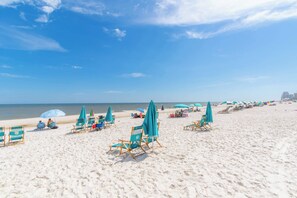 A beach with rows of chairs and umbrellas, a clear sky, and the ocean in the background. - Super Clean, Pool, Beach, Dining, Fun (Orange Beach)