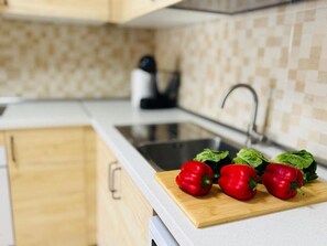 Eine Küche mit einer Holzauskładung, einem Spülbecken und einem Schneidebrett mit roten Paprika und Grünzeug.