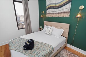 Una camera da letto con un letto, un comodino, una lampada a parete e vista dalla finestra.