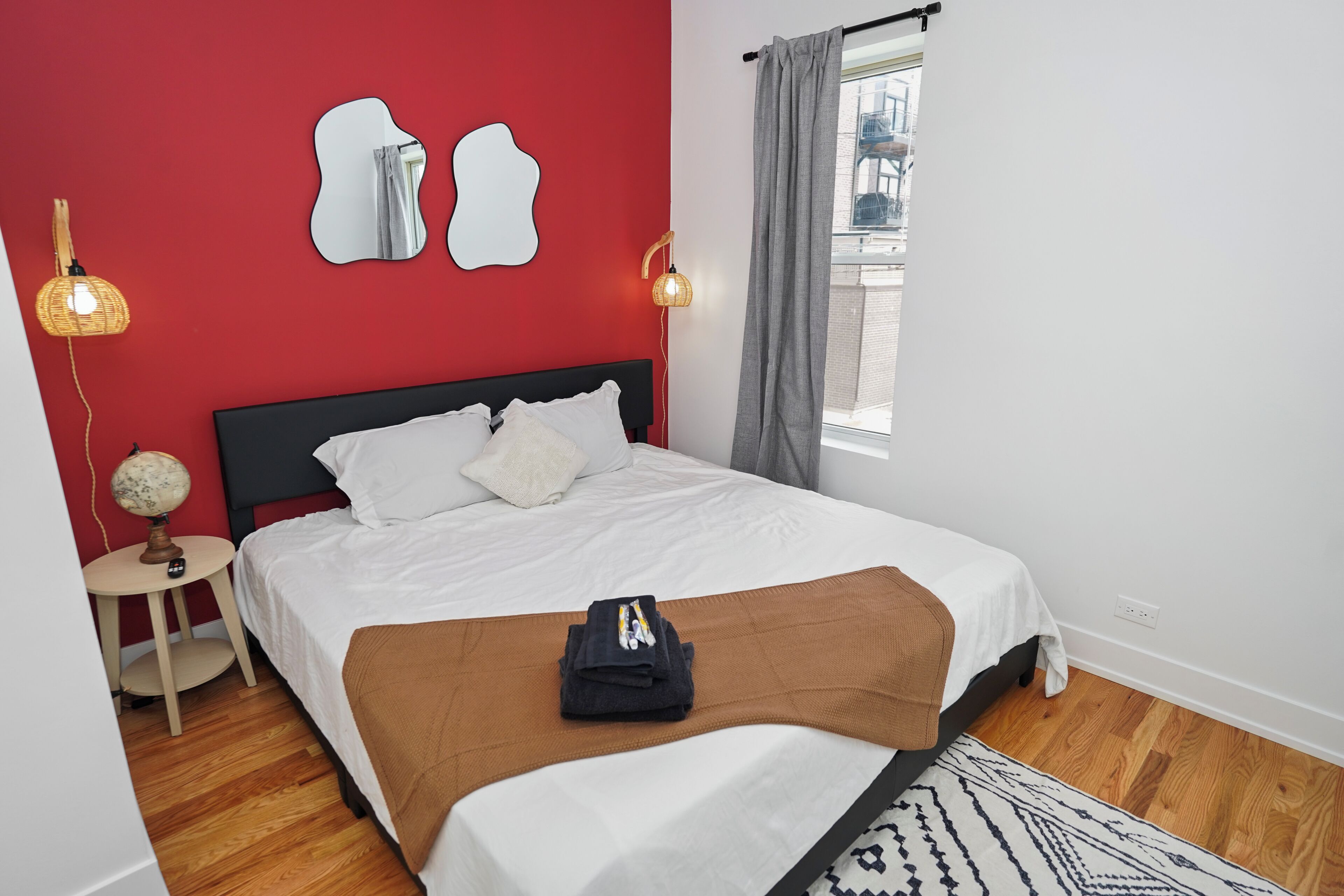 Una cama bien tendida con ropa blanca, un plaid marrón y un pequeño globo terráqueo en una mesita de noche.