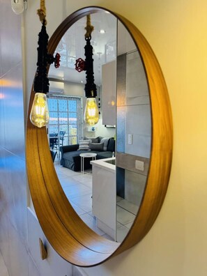 Ein modernes Interieur mit einem gewölbten Spiegel, einer Couch, einem kleinen Tisch und einer Küchenzeile.
