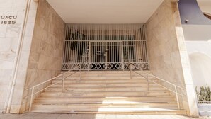 Una serie de escalones de mármol que conducen a una entrada con puerta y barandilla de metal.