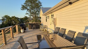 Eine Holzterrasse mit Tisch, Stühlen, einem Grill und einem Whirlpool.