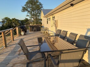 Eine Holzterrasse mit Tisch, Stühlen, einem Grill und einem Whirlpool.