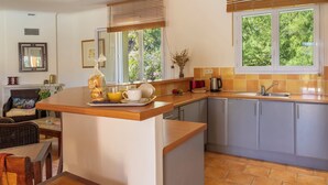 Una cocina con zona de desayuno, un lavabo y una ventana con vistas a zonas verdes.