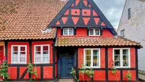 A traditional half-timbered house with a steeply pitched roof, a prominent gable, and a dark blue door. - Historic stay in the heart of Aeroskobing (Ærøskøbing)