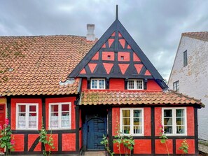 Ein traditionelles Fachwerkhäuschen mit steilem Dach, einem markanten Giebel und einer dunkelblauen Tür.