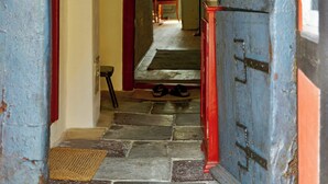 A hallway with a stone archway, a wooden door, and a red wall. - Historic stay in the heart of Aeroskobing (Ærøskøbing)
