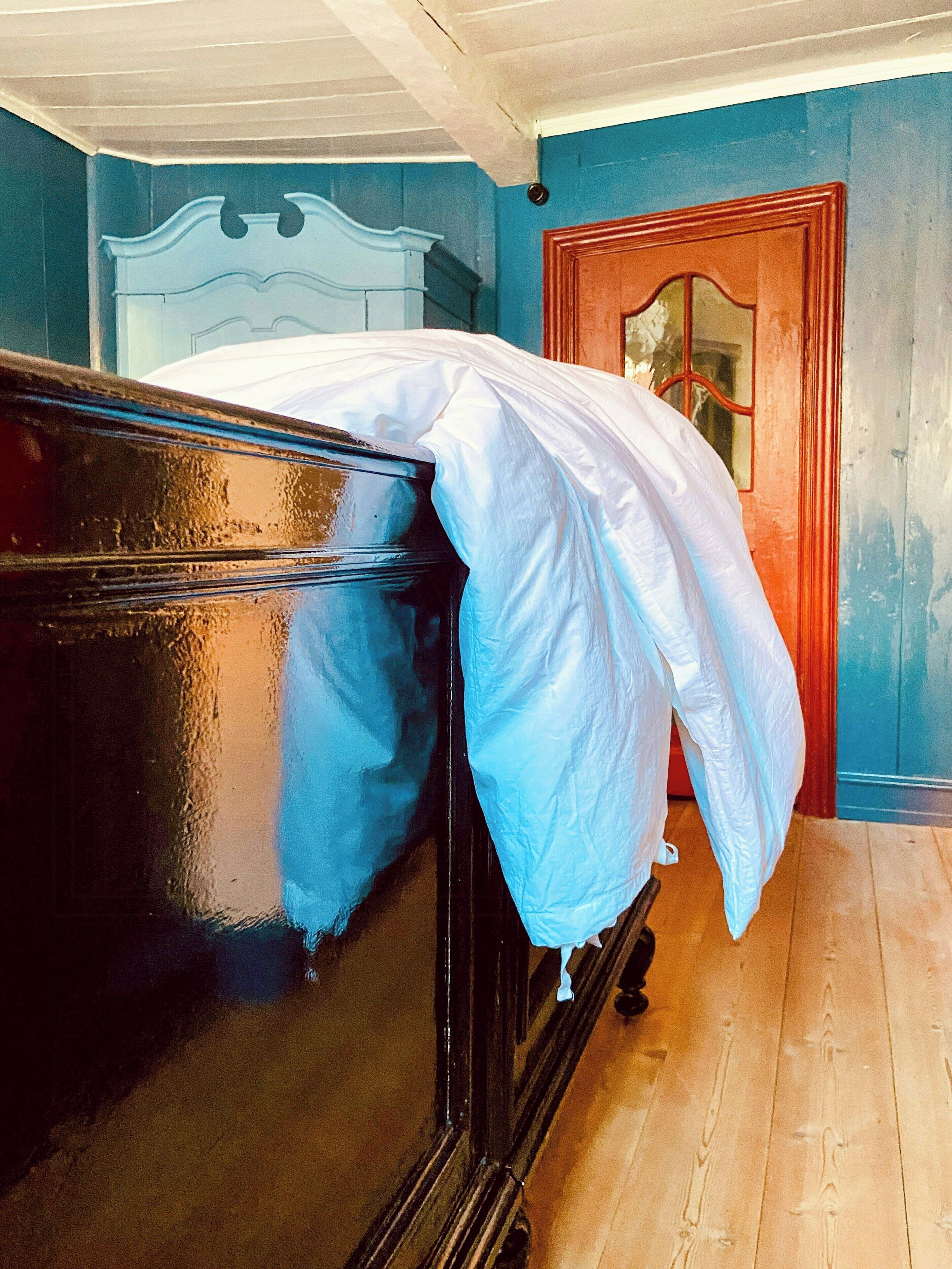 Una habitación con una cama, una puerta de madera y una pared azul.