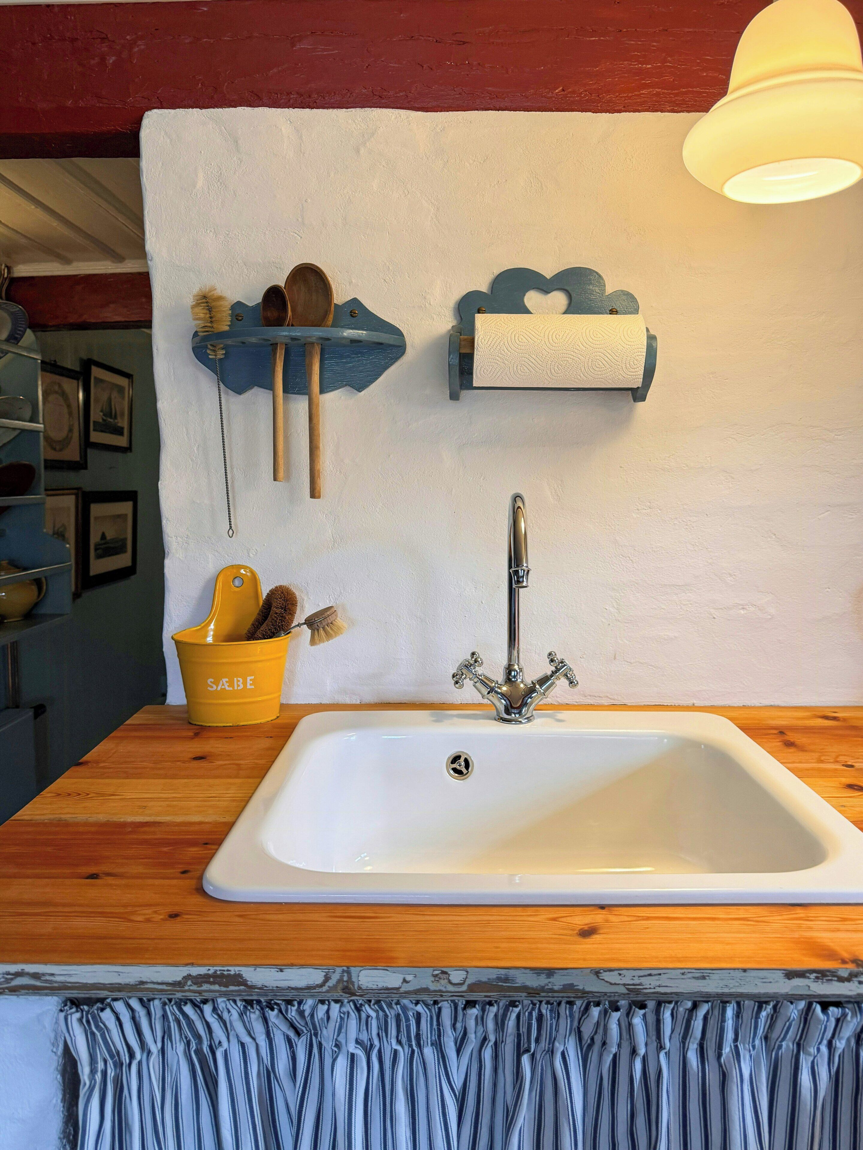 Une cuisine avec un évier blanc, un plan de travail en bois et un luminaire suspendu.