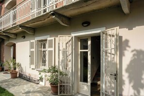 A residential building with a balcony, a door with a metal gate, and potted plants. - Grandmother's house with hot tub in Scurzolengo (Scurzolengo)