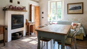 Comedor con una mesa y sillas de madera, chimenea y ventana con vista a la vegetación.