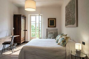 A bedroom with a bed, a desk, a chair, a wardrobe, a radiator, a lamp, and a window. - Grandmother's house with hot tub in Scurzolengo (Scurzolengo)